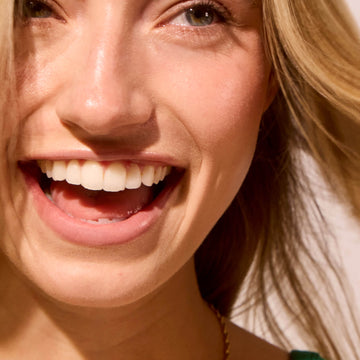 Close-up of a smiling woman focusing on glowy, heathy, bright, hydrated skin